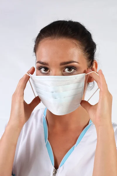 白い制服を着た若い女医が顔にマスクをつけて — ストック写真