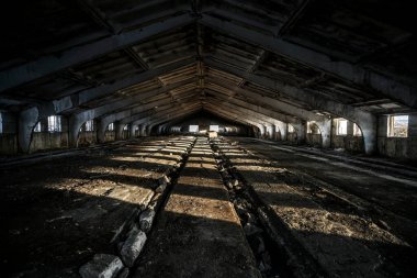 Terk edilmiş eski ahır tuğlası bina çatısı sızdırıyor ve güneş ışığında iç duvarlar yıkılıyor.