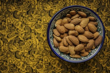 Bademler mavi kasede, kağıt kaplamalı arka plan, üst manzara. Yazı için boş Kopyalama alanı.