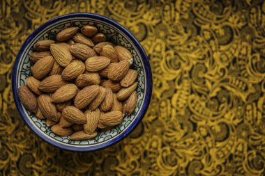 Bademler mavi kasede, kağıt kaplamalı arka plan, üst manzara. Yazı için boş Kopyalama alanı.