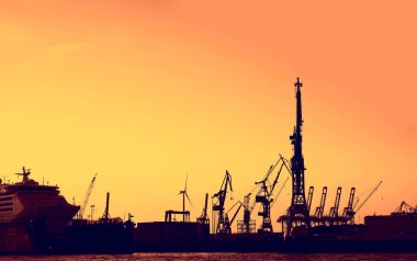 Limandaki vinçler ve gün batımı renkli gökyüzü ve denizde yolcu gemisi parkı. Hamburg, Almanya