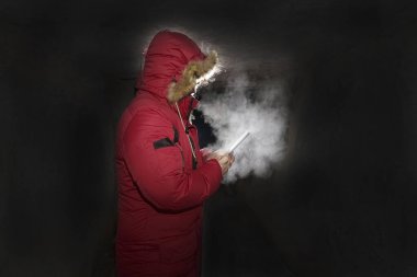 Geceleri karanlık uzayda akıllı telefon kullanan tanınmayan bir adam. nefes almaktan buhar