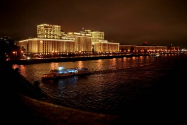 Rusya Savunma Bakanlığı 'nın panoramik manzarası, Novoandreevsky Köprüsü, Moskova. Gece sahnesi. Tekne Moskova nehrinde yol alıyor.
