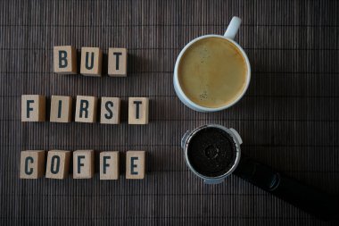 Bambu arka planında kahve fincanının en üst görüntüsü, ama ilk kahveyle, kelimeler. Keçiboynuzu kahve makinesi.