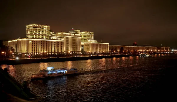 Rusya Savunma Bakanlığı 'nın panoramik manzarası, Novoandreevsky Köprüsü, Moskova. Gece sahnesi. Tekne Moskova nehrinde yol alıyor.