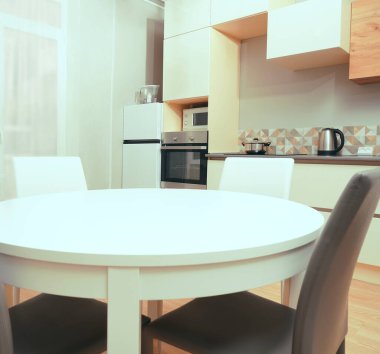 Mutfak odasının beyaz renkli parlak fotoğrafı elektrikli fırın, buzdolabı ve ahşap masa dolapları ve boş masalı diğer ekipmanlar. iç arkaplan