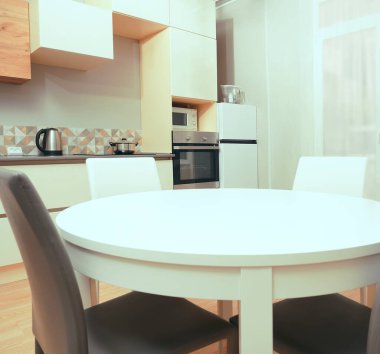 Mutfak odasının beyaz renkli parlak fotoğrafı elektrikli fırın, buzdolabı ve ahşap masa dolapları ve boş masalı diğer ekipmanlar. iç arkaplan