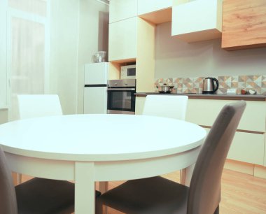 Mutfak odasının beyaz renkli parlak fotoğrafı elektrikli fırın, buzdolabı ve ahşap masa dolapları ve boş masalı diğer ekipmanlar. iç arkaplan