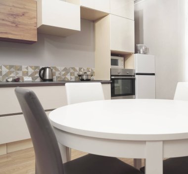 Mutfak odasının beyaz renkli parlak fotoğrafı elektrikli fırın, buzdolabı ve ahşap masa dolapları ve boş masalı diğer ekipmanlar. iç arkaplan