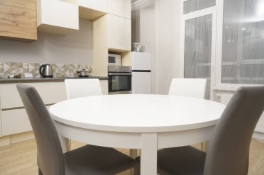 Mutfak odasının beyaz renkli parlak fotoğrafı elektrikli fırın, buzdolabı ve ahşap masa dolapları ve boş masalı diğer ekipmanlar. iç arkaplan