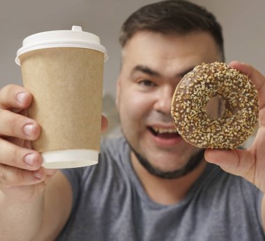 Mutfak geçmişindeki mutlu sakallı adam. Orta yaşlı erkek. Tatlı çörek ve kahve fincanı. Çikolatalı çörek. Diyet yaparken cezbedici. Tatlı hayat..  