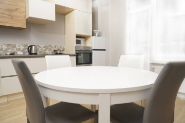 Mutfak odasının beyaz renkli parlak fotoğrafı elektrikli fırın, buzdolabı ve ahşap masa dolapları ve boş masalı diğer ekipmanlar. iç arkaplan