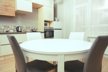 Mutfak odasının beyaz renkli parlak fotoğrafı elektrikli fırın, buzdolabı ve ahşap masa dolapları ve boş masalı diğer ekipmanlar. iç arkaplan