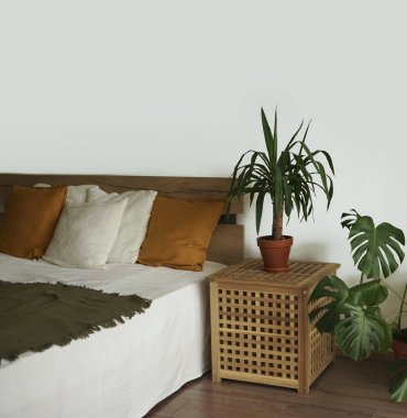 Yumuşak renkli yatak odası. Zarif klasik yatak odasında büyük ve rahat bir çift kişilik yatak odası. Bir sürü yeşil bitki. Doğal ahşap malzemeler.