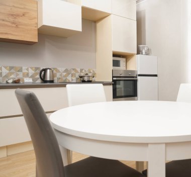 Mutfak odasının beyaz renkli parlak fotoğrafı elektrikli fırın, buzdolabı ve ahşap masa dolapları ve boş masalı diğer ekipmanlar. iç arkaplan