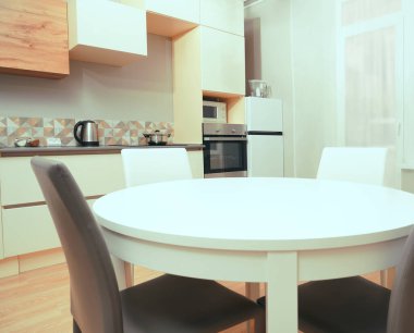 Mutfak odasının beyaz renkli parlak fotoğrafı elektrikli fırın, buzdolabı ve ahşap masa dolapları ve boş masalı diğer ekipmanlar. iç arkaplan