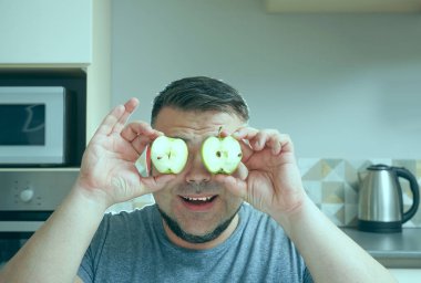 Çekici gülümseyen orta yaşlı adam elinde yeşil taze elmalar tutuyor. Sağlıklı taze gıda konsepti.