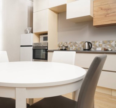 Mutfak odasının beyaz renkli parlak fotoğrafı elektrikli fırın, buzdolabı ve ahşap masa dolapları ve boş masalı diğer ekipmanlar. iç arkaplan