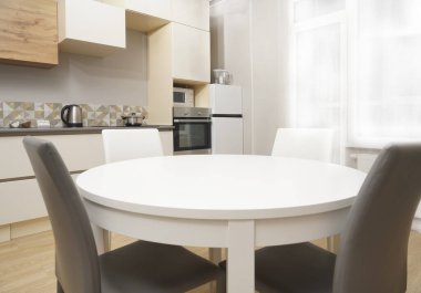 Mutfak odasının beyaz renkli parlak fotoğrafı elektrikli fırın, buzdolabı ve ahşap masa dolapları ve boş masalı diğer ekipmanlar. iç arkaplan