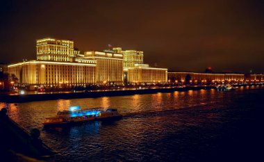 Rusya Savunma Bakanlığı 'nın panoramik manzarası, Novoandreevsky Köprüsü, Moskova. Gece sahnesi. Tekne Moskova nehrinde yol alıyor.