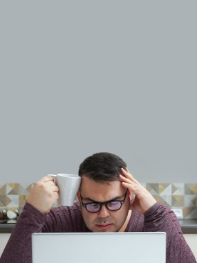 Hüzünlü ve hasta erkek serbest çalışan. Mutfak odasında çalışırken elinde bir fincan sıcak kahve ve dizüstü bilgisayarla dolaşır. 