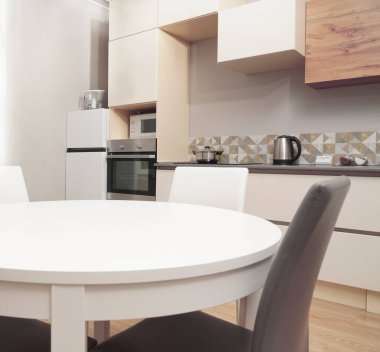 Mutfak odasının beyaz renkli parlak fotoğrafı elektrikli fırın, buzdolabı ve ahşap masa dolapları ve boş masalı diğer ekipmanlar. iç arkaplan