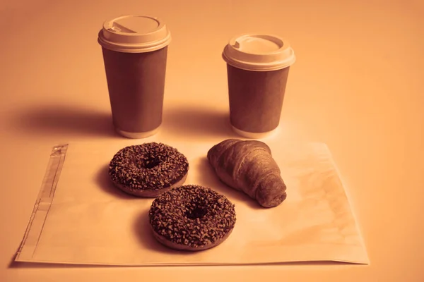 Два Шоколадных Пончика Орехами Круассаном Бумажных Стакана Изолированы Белом Столе — стоковое фото