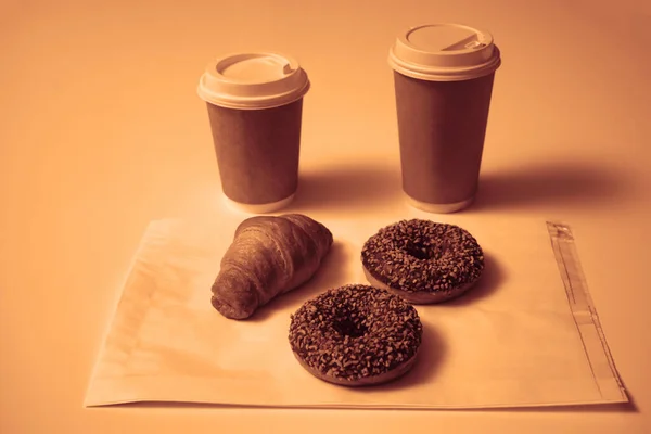 Два Шоколадных Пончика Орехами Круассаном Бумажных Стакана Изолированы Белом Столе — стоковое фото
