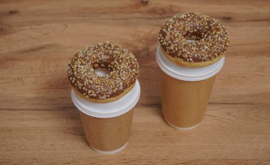 İki çikolatalı çörek ve kahverengi masa arkasında iki fincan kahve. Lezzetli çöller toz fındıkla kaplı, bir sokak fast food 'undan alınmış..