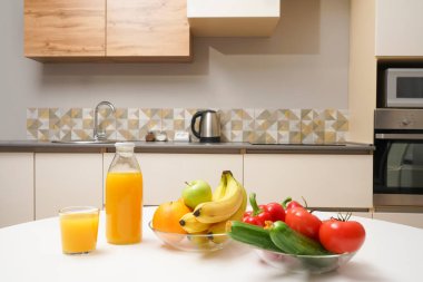 Modern stil mutfak içinde sebzeler ve beyaz ahşap masada meyveler. Parlak beyaz mutfak ve ev eşyaları. Sağlıklı yaşam tarzı kavramı. Yiyecek ve içecek.