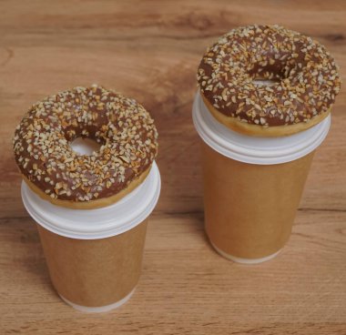 İki çikolatalı çörek ve kahverengi masa arkasında iki fincan kahve. Lezzetli çöller toz fındıkla kaplı, bir sokak fast food 'undan alınmış..