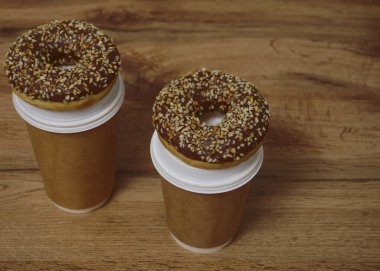 İki çikolatalı çörek ve kahverengi masa arkasında iki fincan kahve. Lezzetli çöller toz fındıkla kaplı, bir sokak fast food 'undan alınmış..