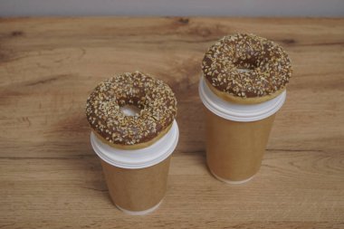 İki çikolatalı çörek ve kahverengi masa arkasında iki fincan kahve. Lezzetli çöller toz fındıkla kaplı, bir sokak fast food 'undan alınmış..