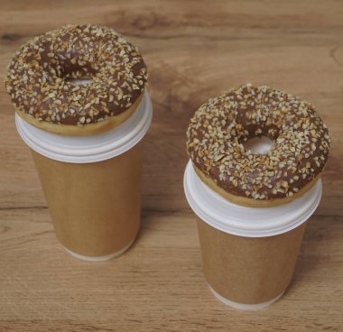 İki çikolatalı çörek ve kahverengi masa arkasında iki fincan kahve. Lezzetli çöller toz fındıkla kaplı, bir sokak fast food 'undan alınmış..