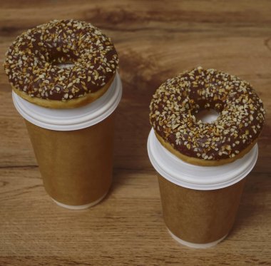 İki çikolatalı çörek ve kahverengi masa arkasında iki fincan kahve. Lezzetli çöller toz fındıkla kaplı, bir sokak fast food 'undan alınmış..