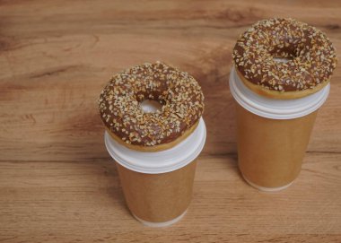 İki çikolatalı çörek ve kahverengi masa arkasında iki fincan kahve. Lezzetli çöller toz fındıkla kaplı, bir sokak fast food 'undan alınmış..