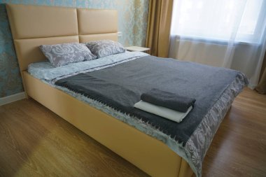 İki havlu çift kişilik yatakta. Beyaz yatak, yakın plan. Yatak başındaki silecekleri temizle. Konsept - otelde çarşaf. Yatak odasının içi. Sabah ışığı