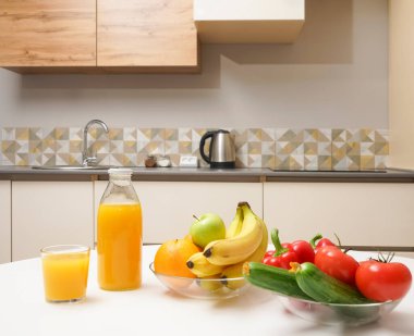 Modern stil mutfak içinde sebzeler ve beyaz ahşap masada meyveler. Parlak beyaz mutfak ve ev eşyaları. Sağlıklı yaşam tarzı kavramı. Yiyecek ve içecek.