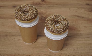 İki çikolatalı çörek ve kahverengi masa arkasında iki fincan kahve. Lezzetli çöller toz fındıkla kaplı, bir sokak fast food 'undan alınmış..