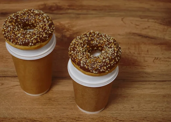 İki çikolatalı çörek ve kahverengi masa arkasında iki fincan kahve. Lezzetli çöller toz fındıkla kaplı, bir sokak fast food 'undan alınmış..