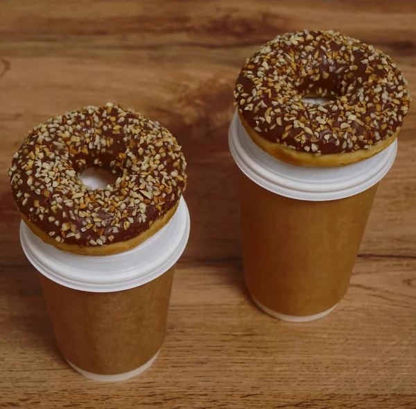 İki çikolatalı çörek ve kahverengi masa arkasında iki fincan kahve. Lezzetli çöller toz fındıkla kaplı, bir sokak fast food 'undan alınmış..