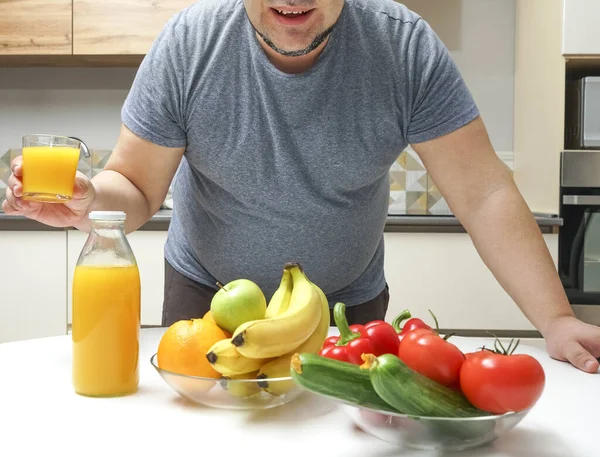 中年男人在桌子上做新鲜榨果汁 水果和蔬菜 瓶子和一杯橙汁 — 图库照片