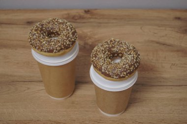 İki çikolatalı çörek ve kahverengi masa arkasında iki fincan kahve. Lezzetli çöller toz fındıkla kaplı, bir sokak fast food 'undan alınmış..