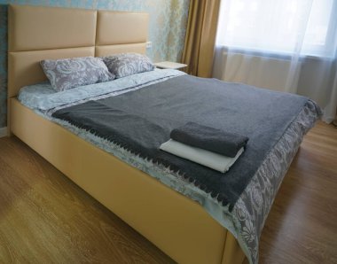 İki havlu çift kişilik yatakta. Beyaz yatak, yakın plan. Yatak başındaki silecekleri temizle. Konsept - otelde çarşaf. Yatak odasının içi. Sabah ışığı