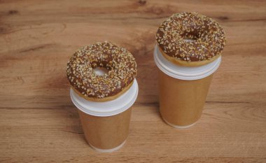 İki çikolatalı çörek ve kahverengi masa arkasında iki fincan kahve. Lezzetli çöller toz fındıkla kaplı, bir sokak fast food 'undan alınmış..