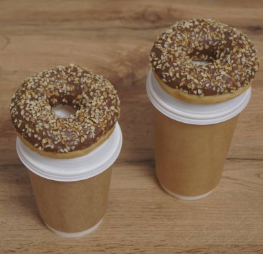 İki çikolatalı çörek ve kahverengi masa arkasında iki fincan kahve. Lezzetli çöller toz fındıkla kaplı, bir sokak fast food 'undan alınmış..