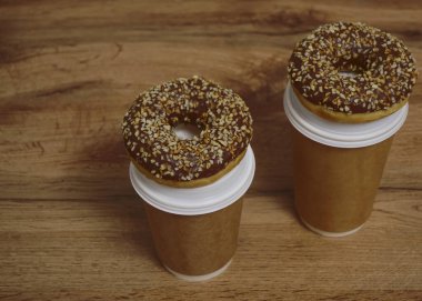 İki çikolatalı çörek ve kahverengi masa arkasında iki fincan kahve. Lezzetli çöller toz fındıkla kaplı, bir sokak fast food 'undan alınmış..