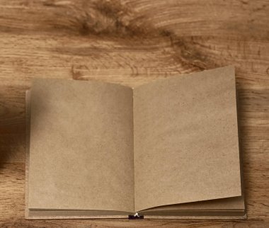 Sarı ahşap masa zemininde açık kahverengi defter, üst manzara. El işi kağıdı. Yazı için boş kopyalama alanı. 