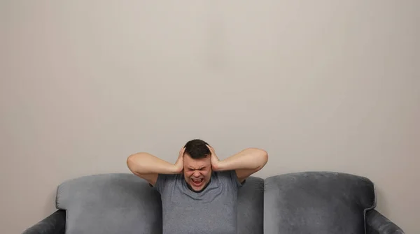 Hombre Sentado Sofá Delante Hombre Habitación Cubriendo Las Orejas Con —  Fotos de Stock