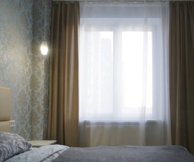 Parlak ve rahat modern yatak odası, soyunma odası, geniş pencere ve geniş pencere pervazı komodinli ve yumuşak yastıklı okumak için..